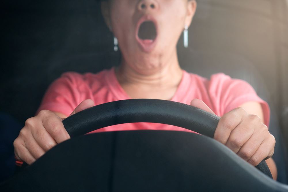 woman driving delivery truck while yawning